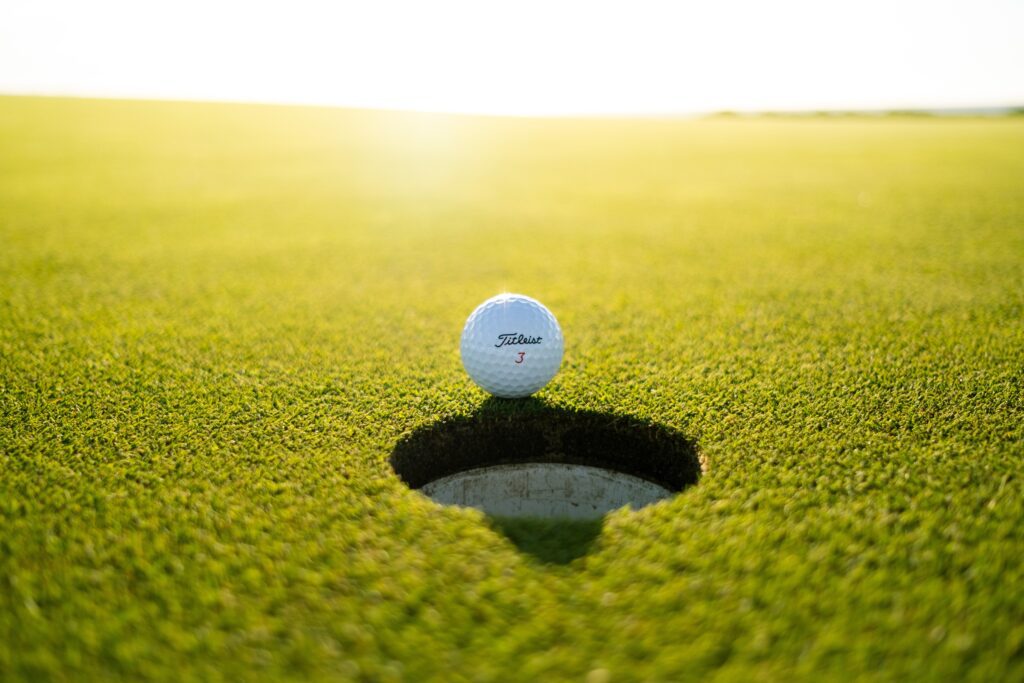 Golf ball sitting on the rim of the hole