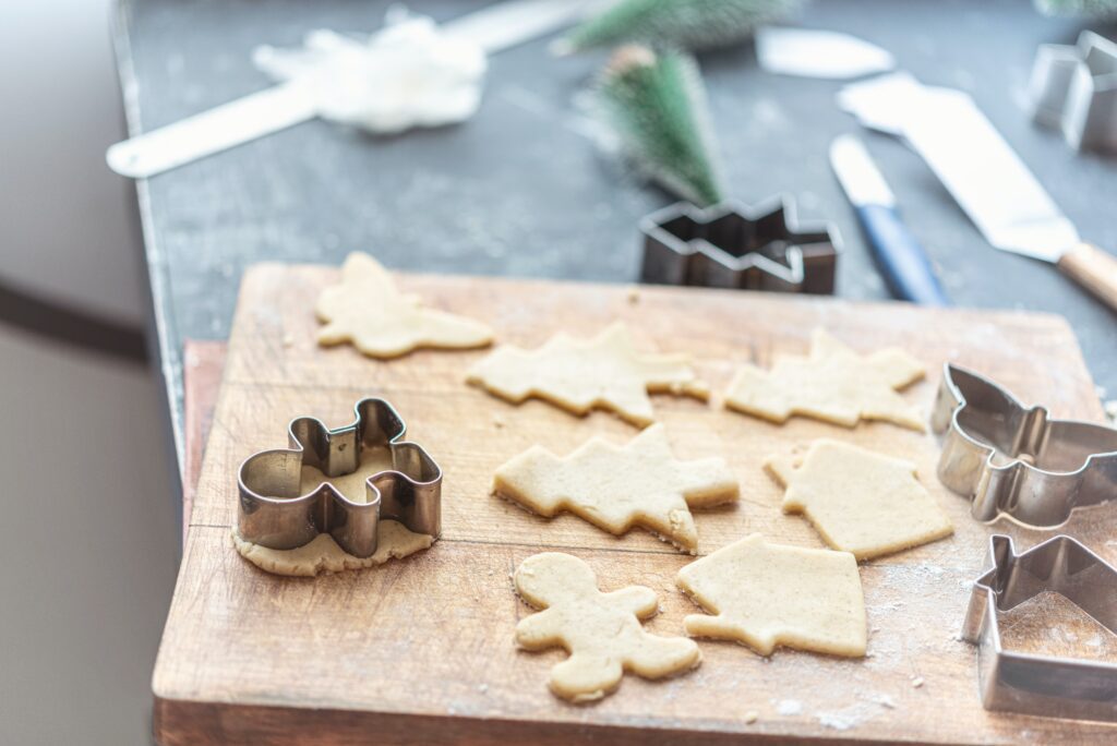 Cookie dough shaped like gingerbread men and christmas trees on a brown cutting board