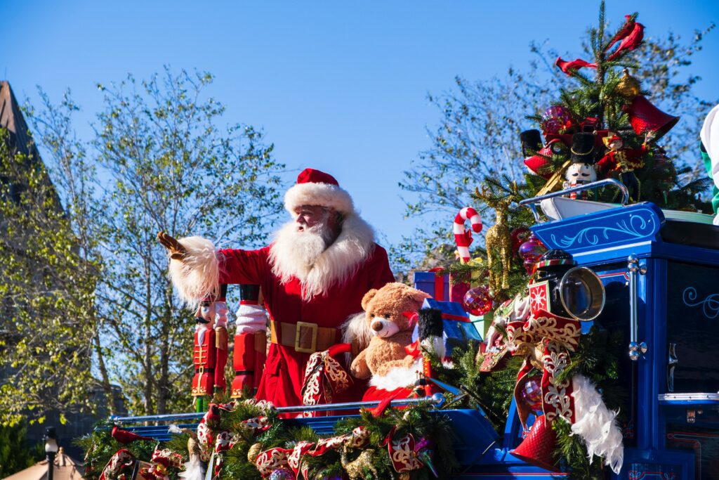 Santa Claus riding a blue decorative float in a holiday parade.