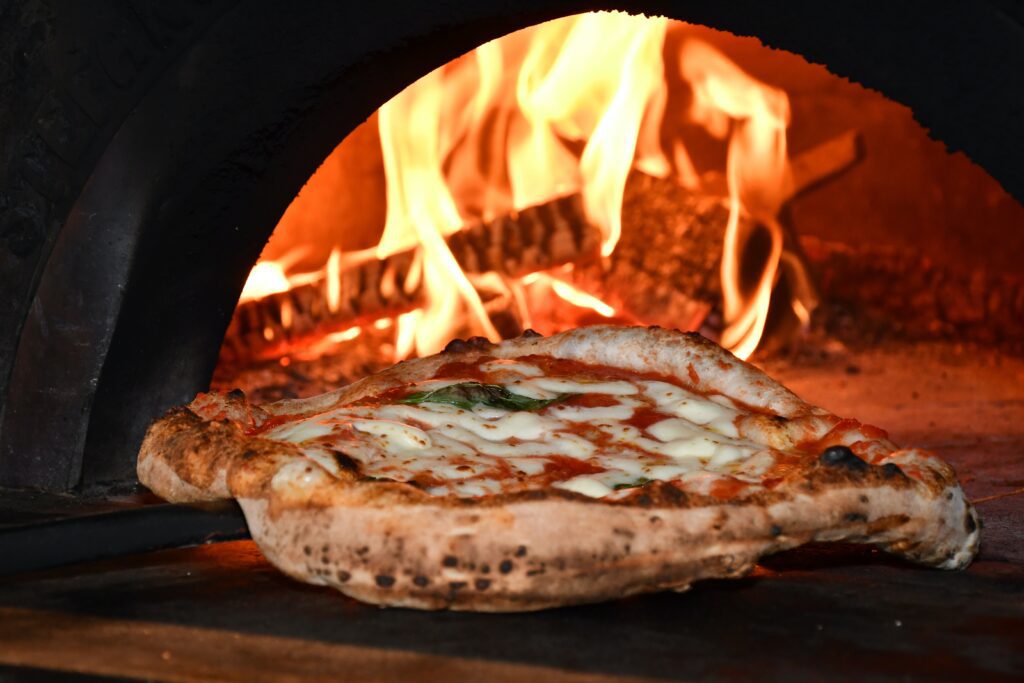 Wood fired pizza coming out of a brick oven