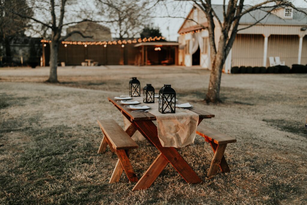 Picnic table set for dinner outside on the farm with a barn in the background.