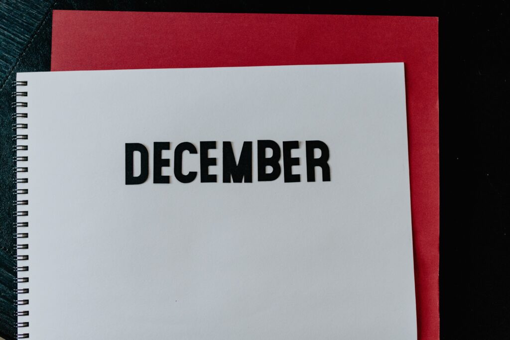 White notebook with December written at the top over a red background.
