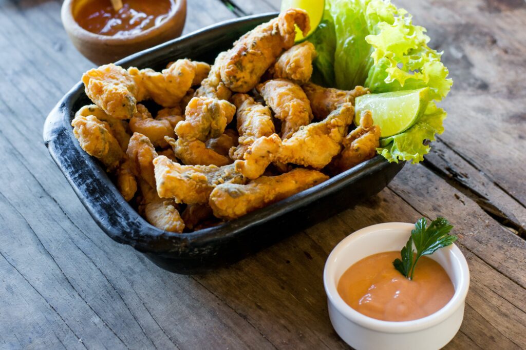 Fried fish in black bowl with two dipping dishes