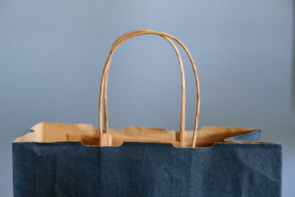 Close up of a blue paper shopping bag with brown rope handle.