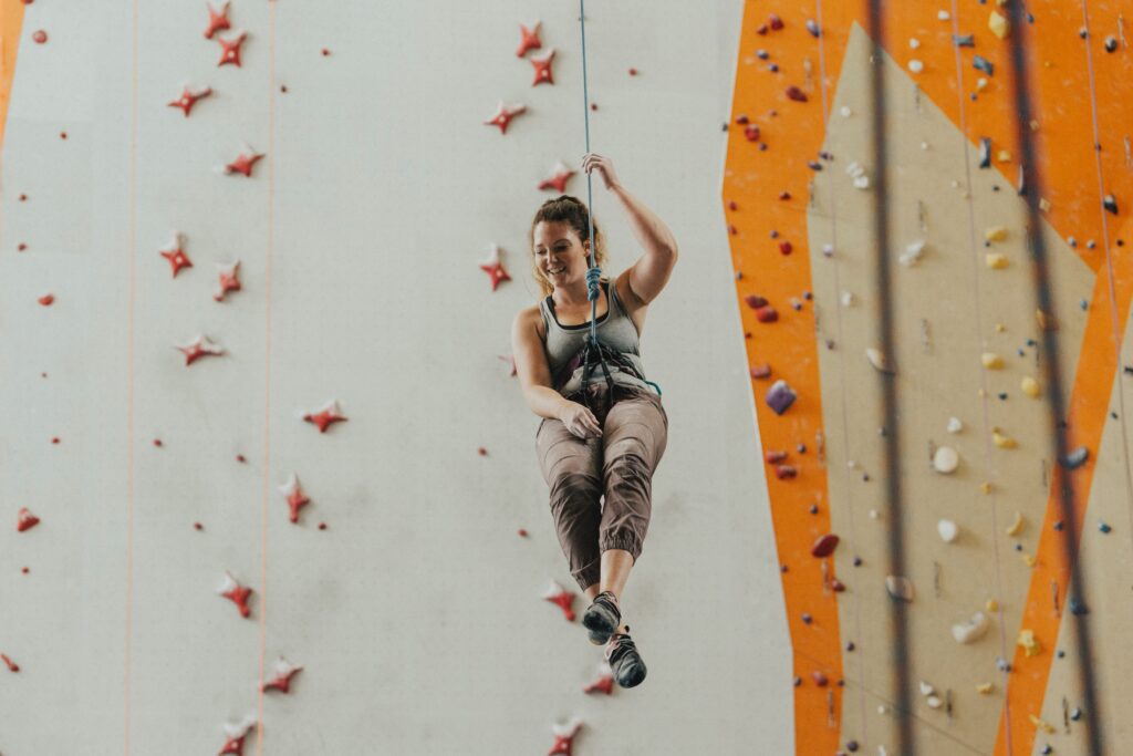 Person hanging on a rope in front of rock climbing wall