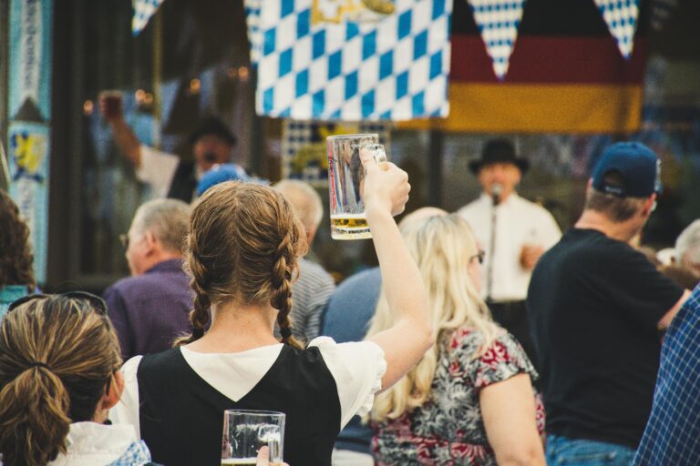 Woman holding beer glass up in a crowd at Oktoberfest autumn fall events in Loudoun County VA by the top local realtor agents team Jean Garrell Group real estate