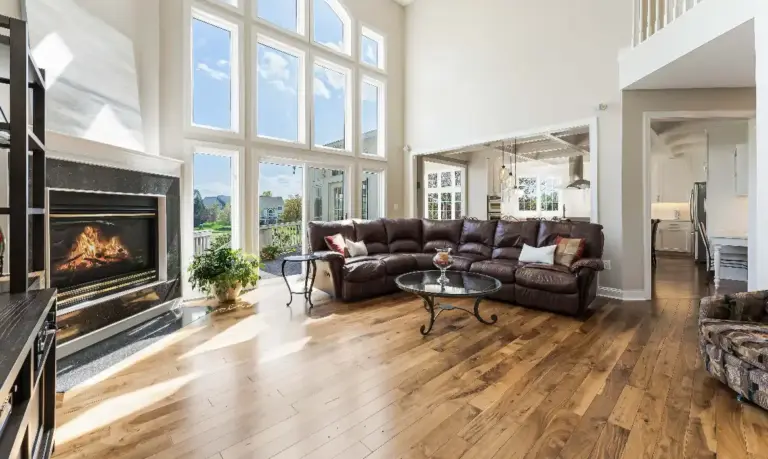 Double-height living room with tall windows, fireplace and a couch, in one of Leesburg and Loudoun County’s best real estate communities