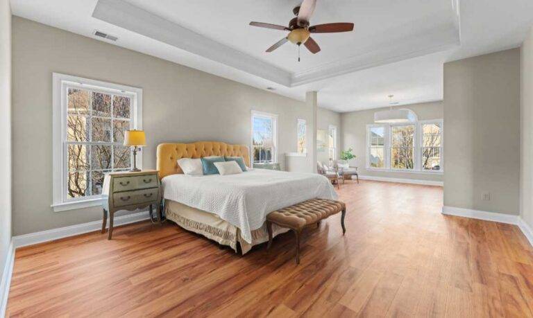 Large primary bedroom suite with sitting area and wood floors in a luxury home in the Loudoun County housing market