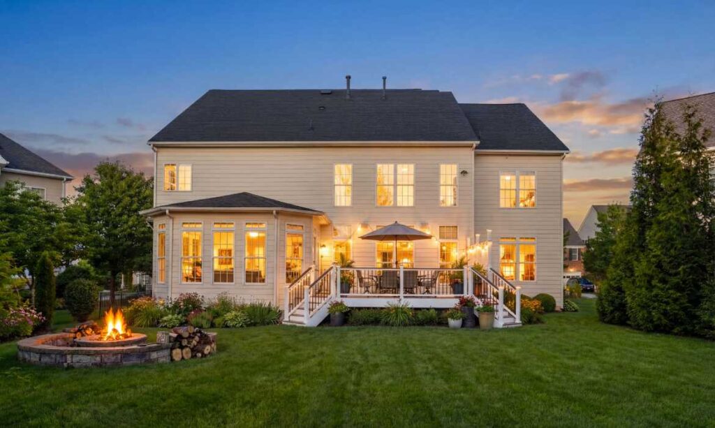 Backyard with deck and fire pit surrounded by trees and lawn in a home for sale by Jean Garrell best real estate agents in Lansdowne on the Potomac