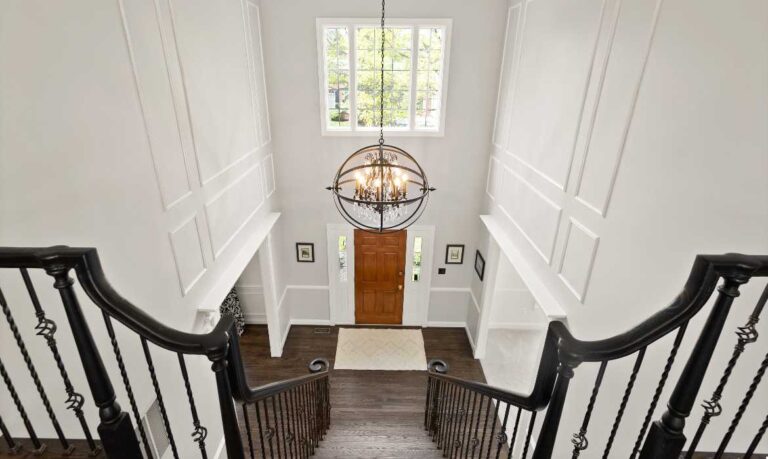View from atop elegant stairs to a double-height foyer with white paint and clean everything, listed by the best Leesburg real estate agent, Jean Garrell