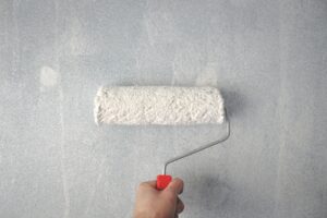 Paint roller on a wall, representing smart improvements and preparations before you sell your Loudoun County, VA home