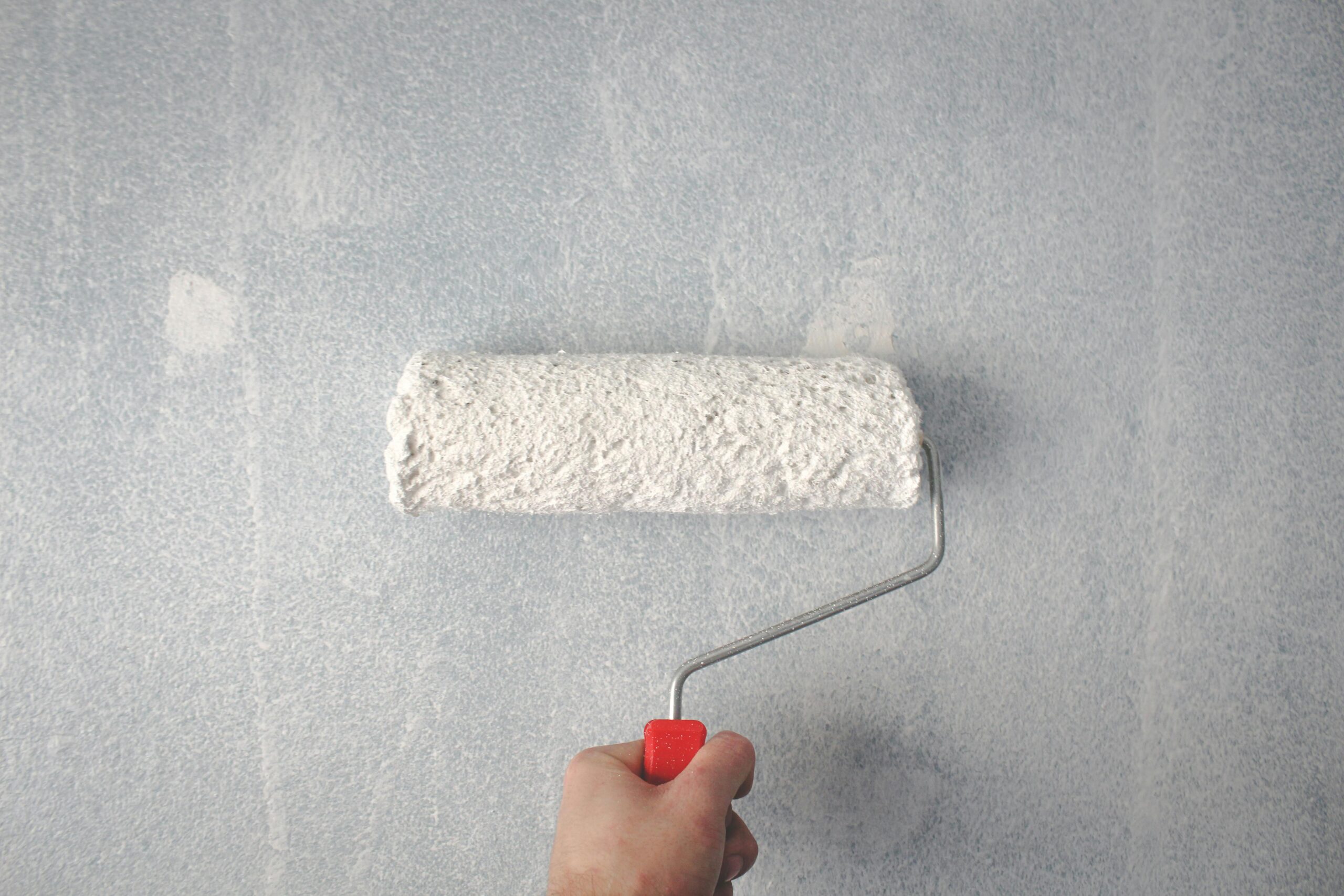 Paint roller on a wall, representing smart improvements and preparations before you sell your Loudoun County, VA home