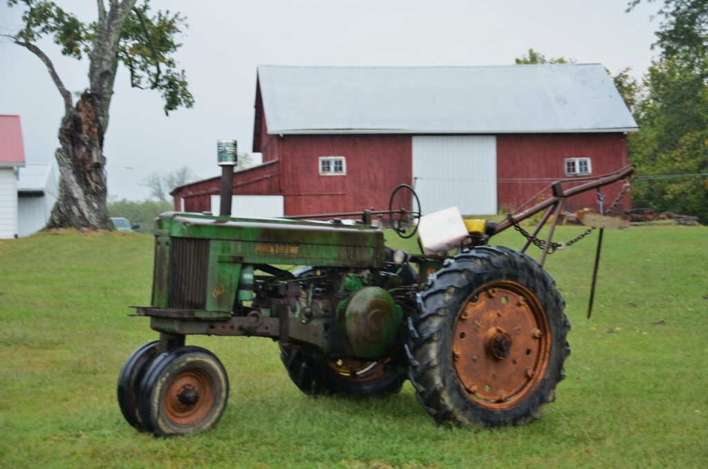 Green tractor in front of a red barn representing Loudoun County farm history near Dulles