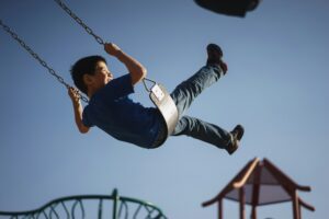 A young boy sitting on a swing at a playground to depict the family fun around Potomac Falls, Virginia.