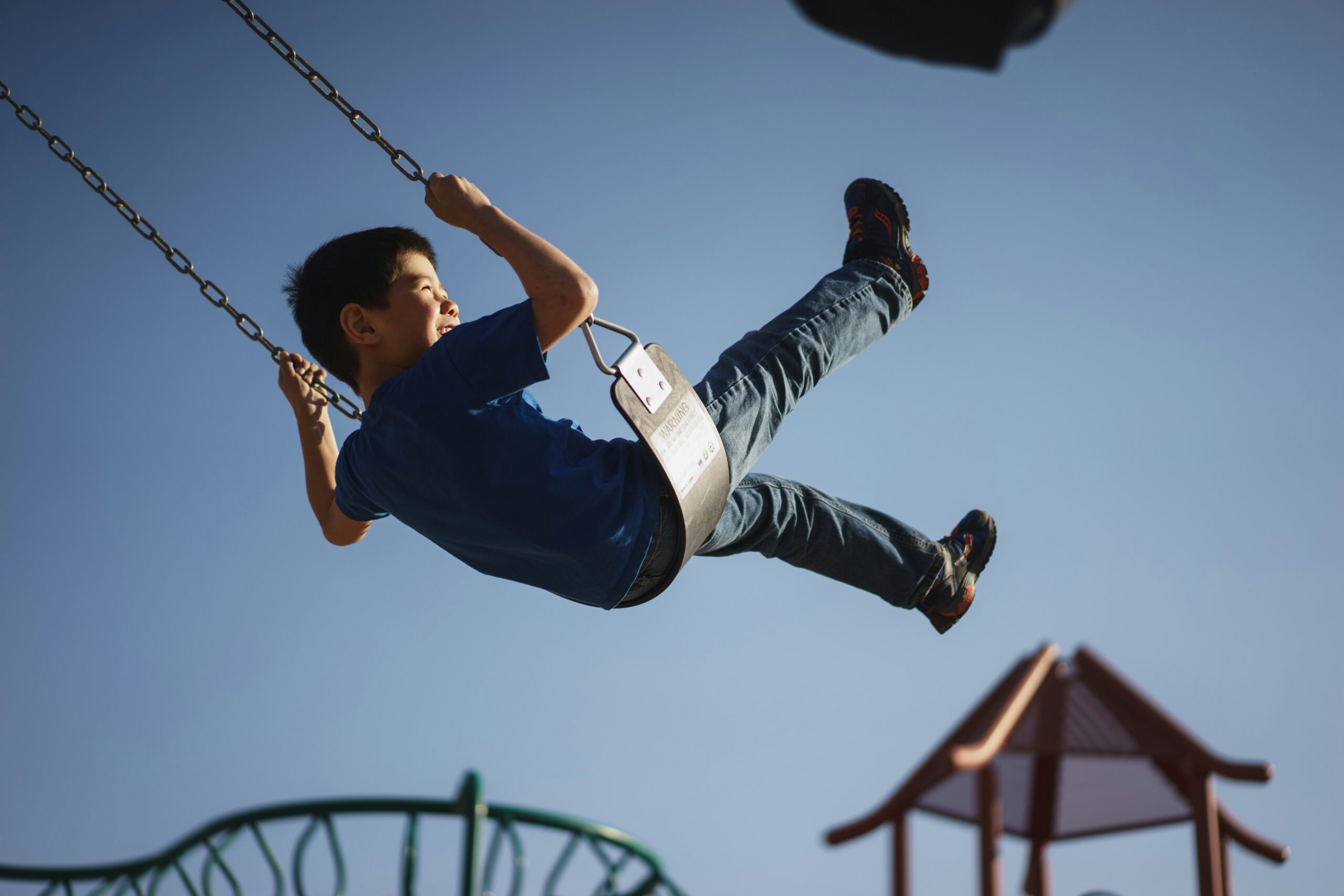 A young boy sitting on a swing at a playground to depict the family fun around Potomac Falls, Virginia.