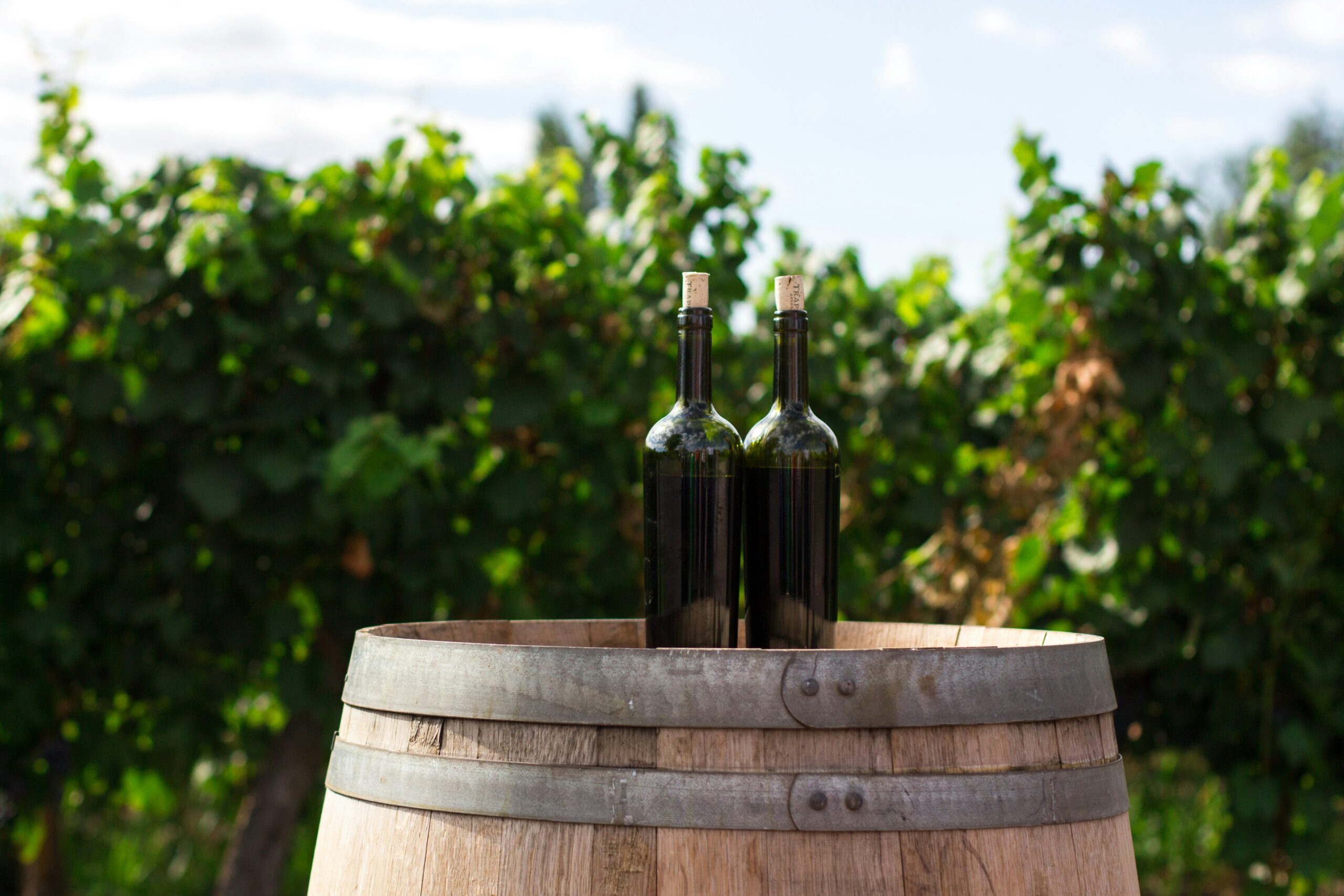 Wine bottles on a wooden barrel representing Purcellville wineries and local vineyards in Virginia.
